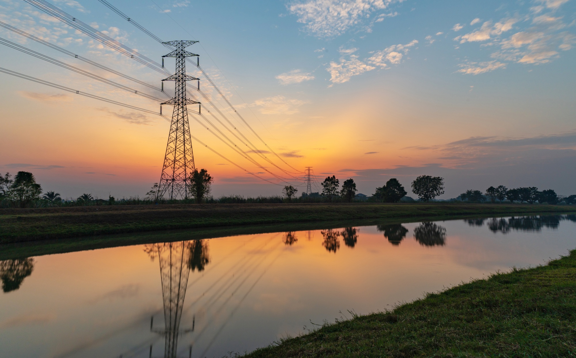 The silhouette of a high-voltage electric pole in the countryside